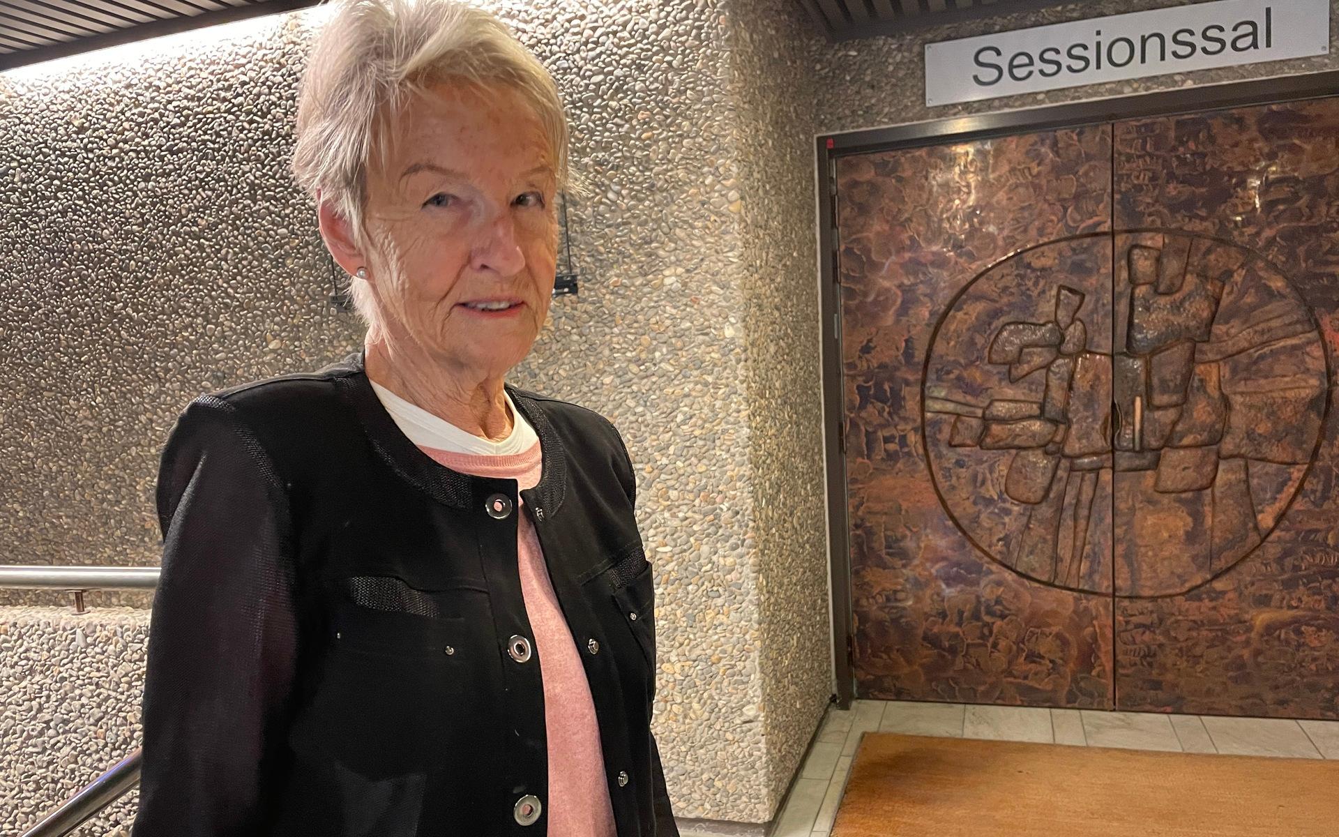 Moderaten Inger René står utanför sessionssalen till kommunfullmäktige i Partille. dörren är skapad av Acke Jansson som också står bakom skulpturen Valen utanför kommunhuset.