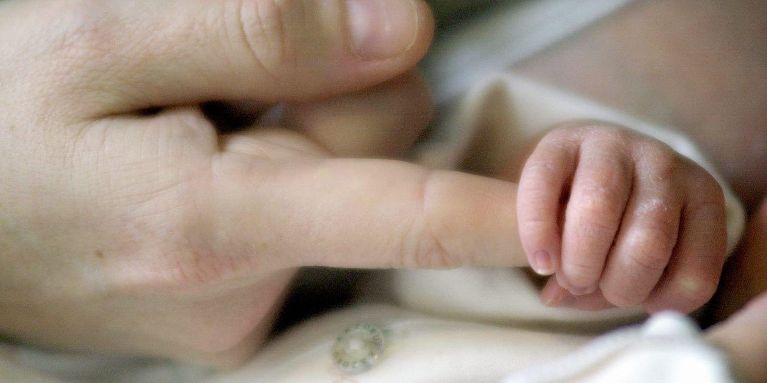 En bebishand håller ett vuxet finger. 